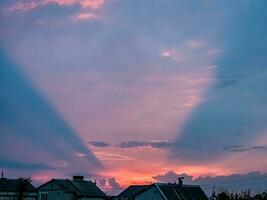 Unusual sunset. Pink conical optical effect from the rays of the setting sun in the clouds. photo