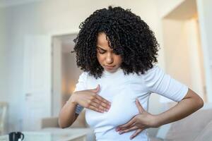 Young African American woman palpating her breast by herself that she concern about breast cancer. Healthcare and breast cancer concept photo