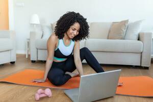 Young woman exercising at home in a living room. Video lesson. Young woman repeating exercises while watching online workout session. Beautiful young woman doing fitness exercise at home photo