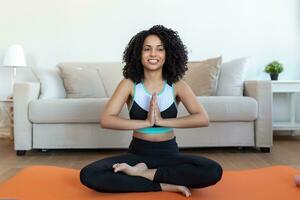 Young beautiful woman in the prayer position. Woman practicing yoga, relaxing in prayer position on mat, Padmasana exercise girl wearing sportswear working out, meditating in yoga studio or at home photo