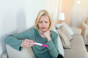 Shocked woman looking at control line on pregnancy test. Single sad woman complaining holding a pregnancy test . Depressed woman holding negative pregnancy test. photo