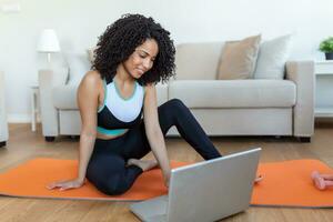 Young woman exercising at home in a living room. Video lesson. Young woman repeating exercises while watching online workout session. Beautiful young woman doing fitness exercise at home photo