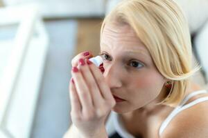 Woman using eye drop, woman dropping eye lubricant to treat dry eye or allergy sick girl treating eyeball irritation or inflammation sick woman suffering from irritated eye, optical symptoms photo