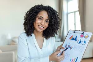 Focused business woman presenting charts and graphs on video call online. Young business woman having conference call with client on laptop. Young woman explaining how business work photo