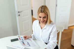 A young woman works remotely on a laptop in her apartment. A lady during a video business briefing at home. A pretty female student listening to an online lecture. photo