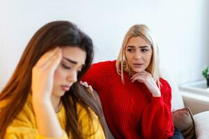 Sad women and supporting friends trying to solve a problem. Two sad diverse women talking at home. Female friends supporting each other. Problems, friendship and care concept photo