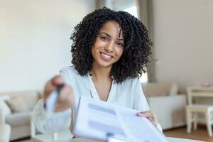 Sign Here. Young smiling confident woman pointing to a contract, sheet of paper, holding a pen, looking and showing it at camera. Presentation, Agreement, Business Concept. photo