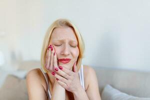 Portrait of unhappy caucasian woman suffering from toothache at home. Healthcare, dental health and problem concept. Stock photo