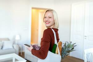 Beautiful young woman with vegetables in grocery bag at home. Portrait of a happy young woman holding a bag full of healthy vegetables at home. Healthy food first photo