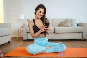 Beautiful woman in headphones looking at smartphone, listening music and relaxing after training photo