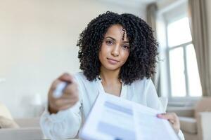 Sign Here. Young smiling confident woman pointing to a contract, sheet of paper, holding a pen, looking and showing it at camera. Presentation, Agreement, Business Concept. photo