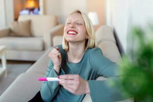 Young happy woman holding positive pregnancy test, shallow depth of field. Happy that she is going to have baby. Finally pregnant. photo