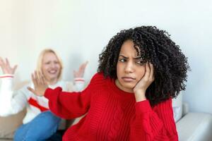 Dont want to hear. Unhappy disturbed tired woman communicating with her friend sitting near her on the sofa shaking her hands. Friends arguing on sofa at home. Two female friends arguing photo