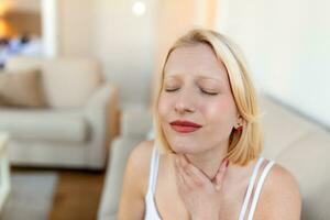 Close up of young woman rubbing her inflamed tonsils, tonsilitis problem, cropped. Woman with thyroid gland problem, touching her neck, girl has a sore throat photo