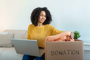 Woman holding cardboard donation box full with clothes. Concept of volunteering work, donation and clothes recycling. Helping poor people photo