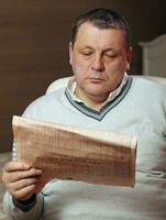 retrato de mayor hombre leyendo periódico a hogar. foto