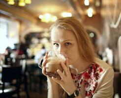 niña es Bebiendo latté en cafetería. foto
