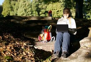 Young woman working outdoors on a laptop photo