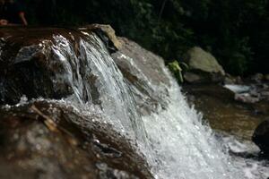 Close-up view of clear water cascading down river rocks photo