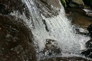 Close-up view of clear water cascading down river rocks photo