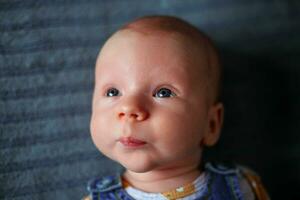 A little boy, newborn, with beautiful blue eyes looks into the distance photo