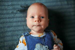 Little boy, newborn, with beautiful blue eyes looks at the camera photo