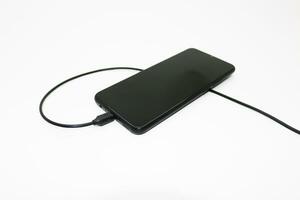 Black mobile phone being charged photo