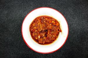 Java spicy chili sauce in a white plate on a black background photo