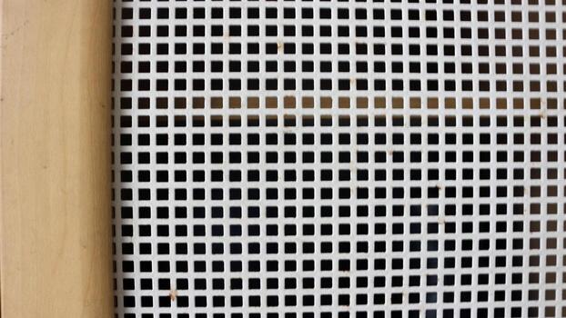 Close-up view of wooden shoe rack with white mesh pattern photo