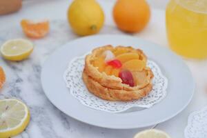 Fruta tarta en un blanco plato con limones y mandarinas foto