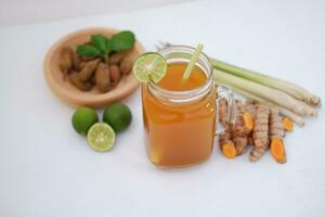 Fresh ginger and lemon juice in a glass jar with ginger roots on white background. photo