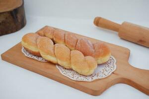 Bread donuts on the wooden table with wooden rolling pin. photo