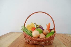 Vegetables in a basket on wooden background. Healthy food concept. photo