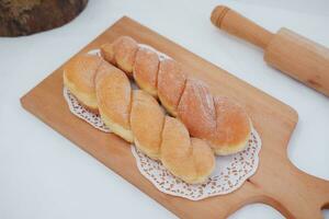 Bread donuts on the wooden table with wooden rolling pin. photo