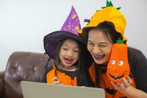 Happy Mother and daughter in witch costume look computer meeting with friend. photo