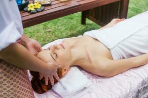 joven hermosa mujer relajante en spa masaje fuera de en tropical jardín. foto