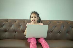 Asian girl sitting on couch with computer enjoy playing game photo