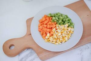 congelado vegetales en un blanco plato en un blanco mármol mesa. foto