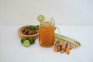 Fresh ginger and lemon juice in a glass jar with ginger roots on white background. photo
