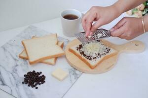 Woman's hands making toast with butter and chocolate on white background. photo