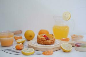 Homemade lemon tart with fresh fruit and orange juice on white background photo