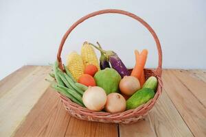 Vegetables in a basket on wooden background. Healthy food concept. photo