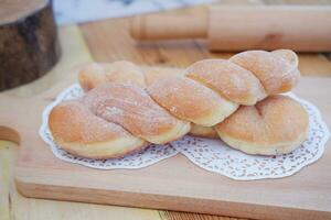 Bread donuts on the wooden table with wooden rolling pin. photo