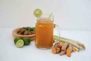 Fresh ginger and lemon juice in a glass jar with ginger roots on white background. photo