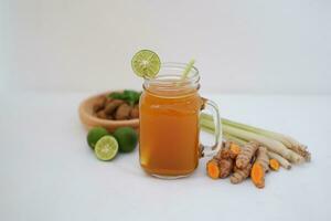 Fresh ginger and lemon juice in a glass jar with ginger roots on white background. photo