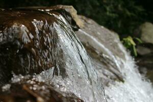 Close-up view of clear water cascading down river rocks photo