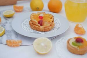 Fruit tart on a white plate with lemons and tangerines photo