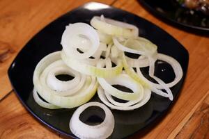 Sliced onions on a black plate on a wooden table photo