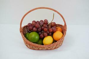 Fruits in a basket on a white background. Orange, grape, lemon. photo