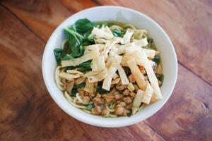 Fried noodle in white bowl on wooden table photo